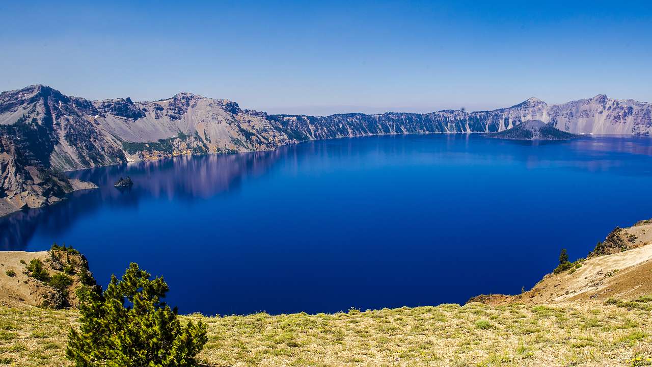 Aerial view of a lake with deep blue water in a volcano crater against a clear sky