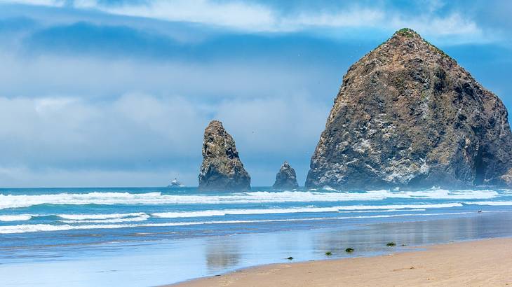 Three monolithic rock formations of different sizes on a beach