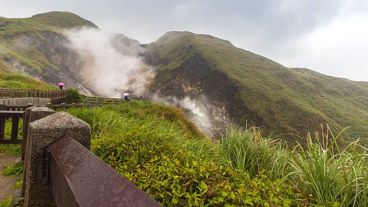 Walking path on the left with people in a volcanic mountain range in Taiwan