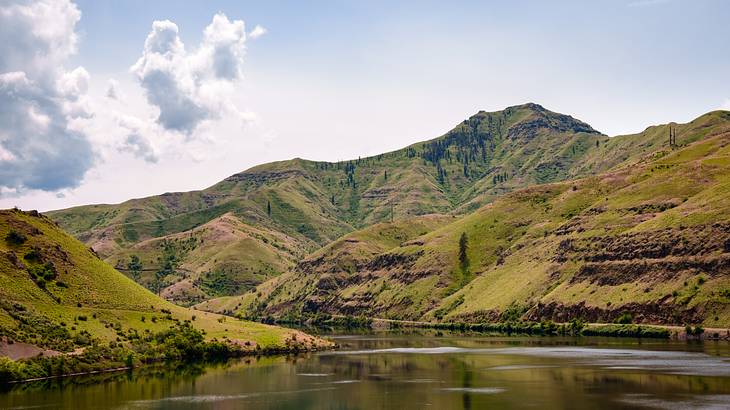 Some clouds above green mountains and a river below