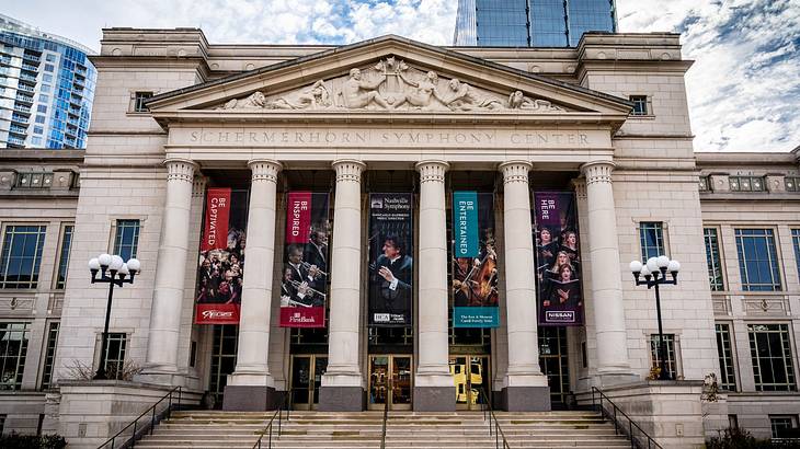 A stone building with columns, carvings, and colorful banners hanging in front