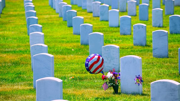 Rows of gravestones on the grass, colorful flowers, a balloon, and a pinwheel