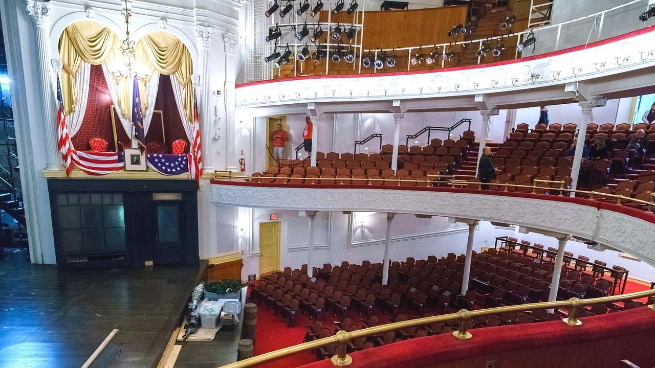 An old-fashioned theater with red seats and white balconies