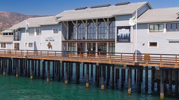 A warehouse-like building with a wall of windows in the center on top of a pier