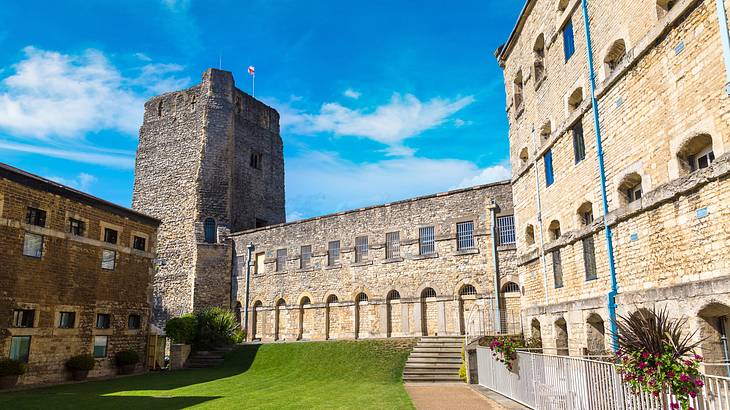 A green courtyard next to an old castle with a tower with a flag on top