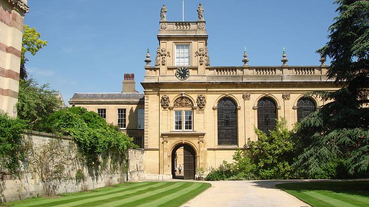 A large path with manicured lawns on the side next to an old building