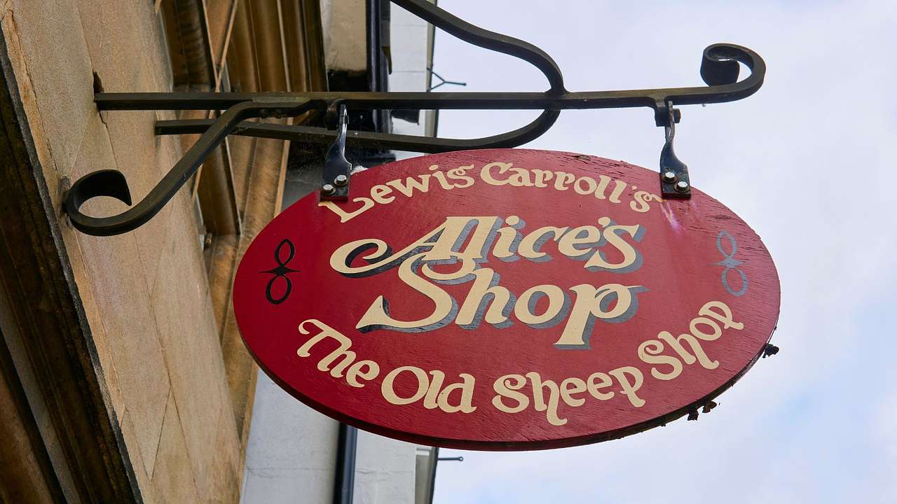 A red sign on a metal frame that says "Lewis Carroll's Alice's Shop"