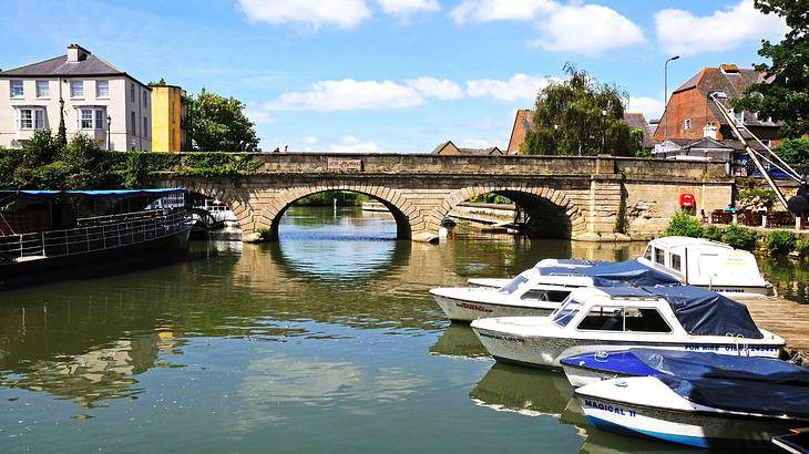 A stone bridge connecting two sides across a river with several boats in it