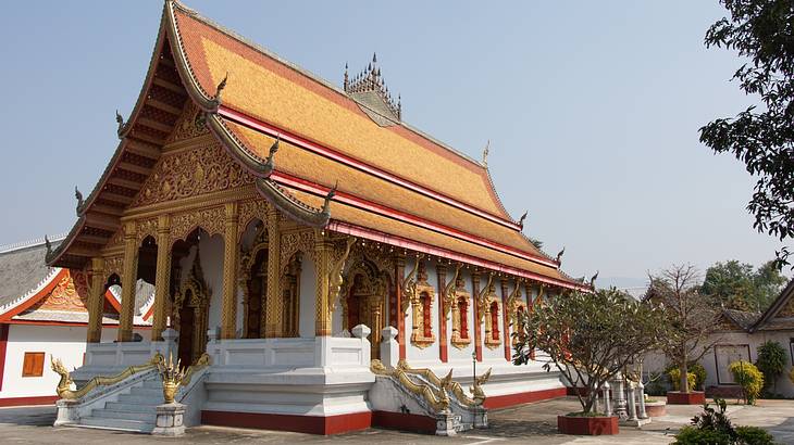 A golden temple with intricate carvings and dragon sculptures on the stair railings