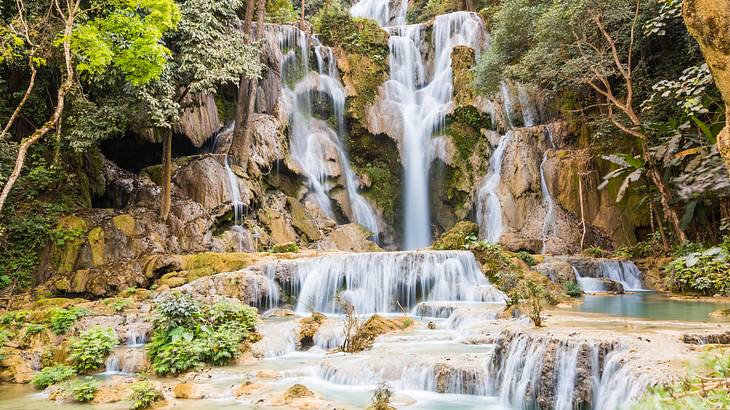 A small waterfall with outcroppings, creating several levels, and trees on the side