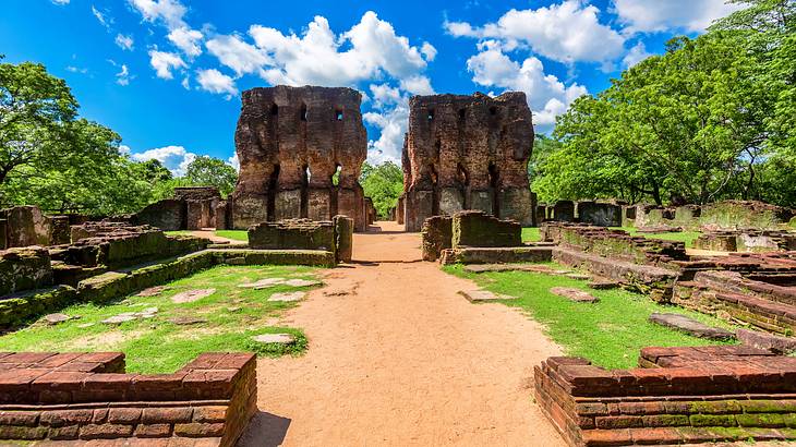 Eight tall brick pillars surrounded by trees, grass, and brick structures