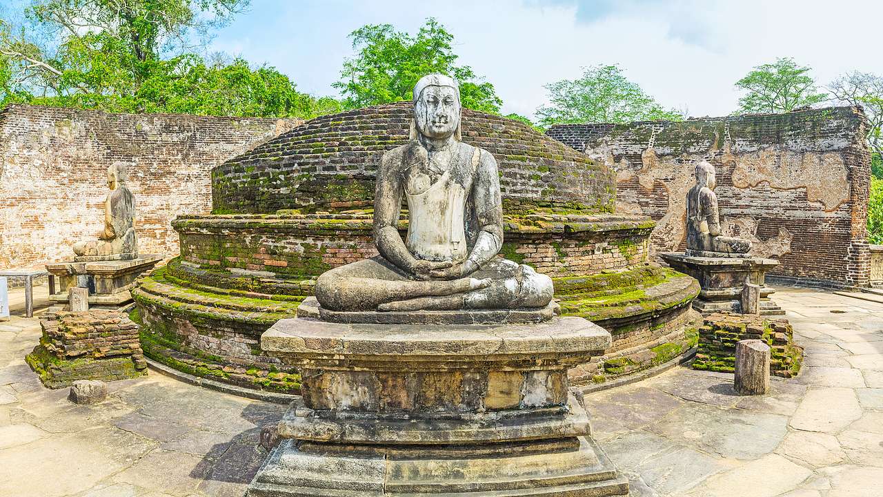 Buddha-style statues sitting on rectangular stone platforms encircling a stone dome