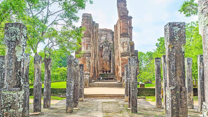 A brick statue with tall pillars on the side and short pillars in front next to trees