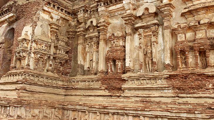 An ancient brick structure with human statues and figurines engraved on its walls