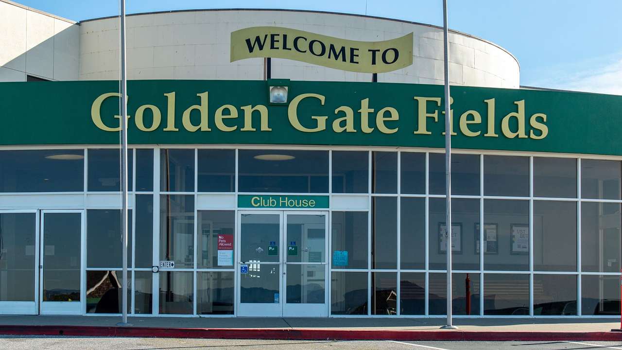 A building with a board that reads "Welcome to Golden Gate Fields," and two flags