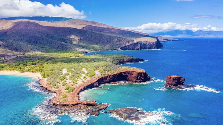 An aerial view of a body of water next to rocks, a cliff, and greenery