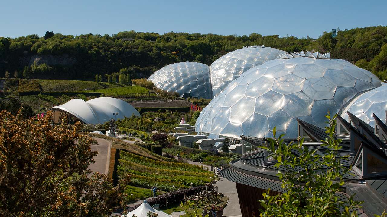 A park with large white domes surrounded by a building, a walkway, and greenery
