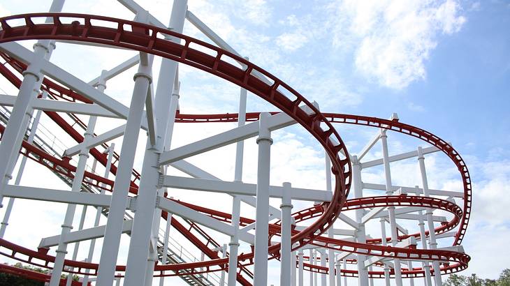 A long rollercoaster's white and red rail as seen from below