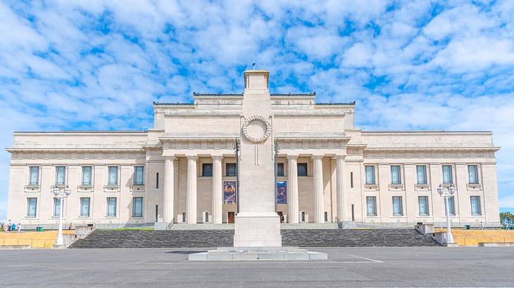 A large stone building with columns and a stone memorial obelisk in front