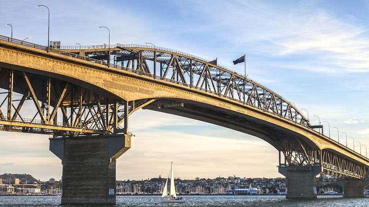 An arched steel bridge over the water at sunset