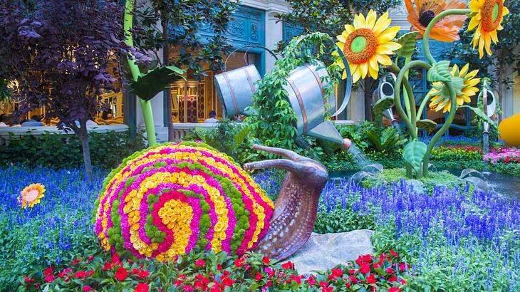 A colorful indoor garden with flowers and a large snail sculpture