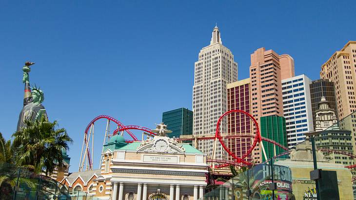 An amusement ride with twisting and looping tracks amidst buildings on a sunny day