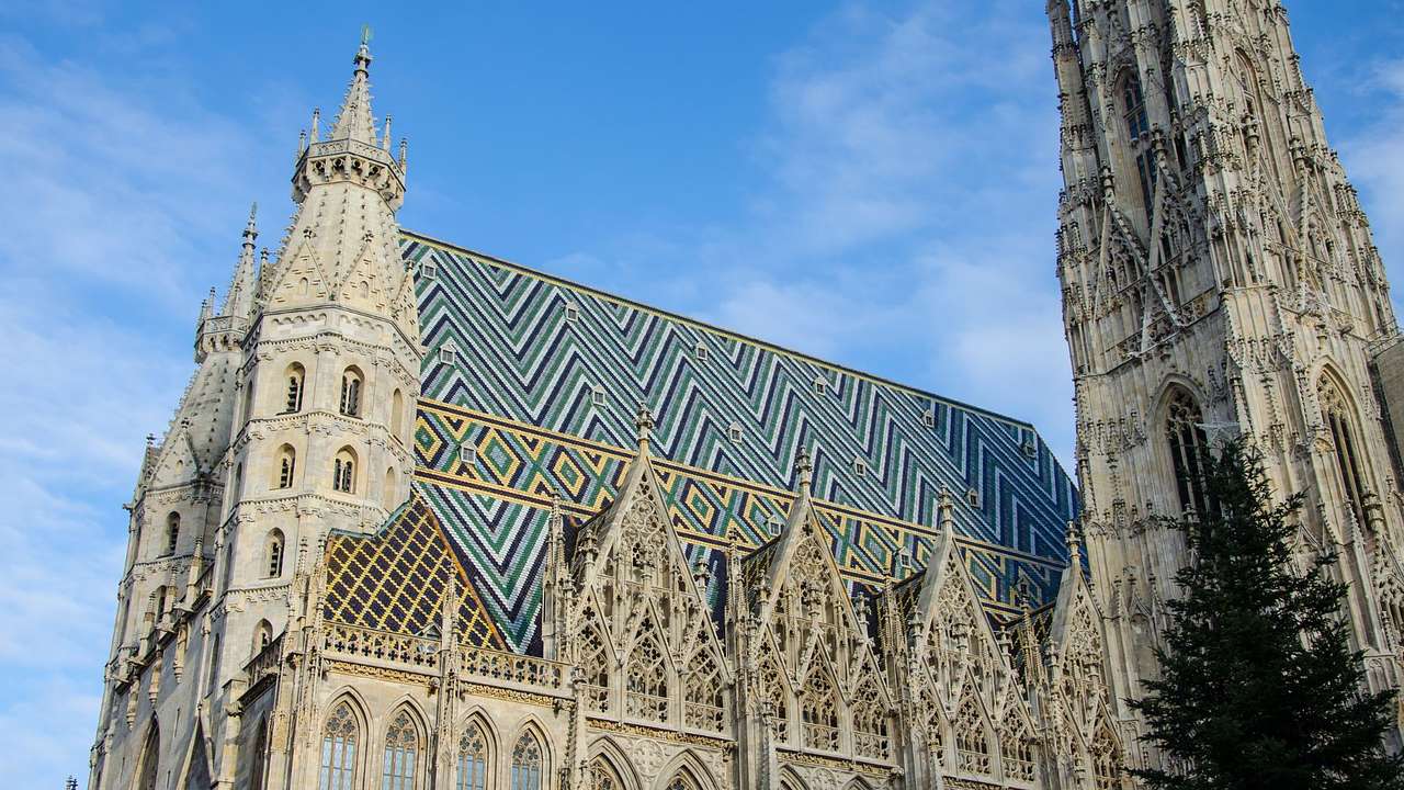 A Gothic cathedral with several towers and colourful mosaic tiles on its roof