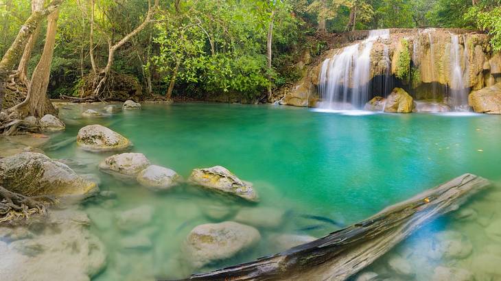 Water flowing down rocks into a turquoise pool of water surrounded by lush greenery