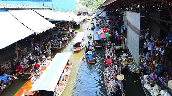 Boats with tourists going down the middle of market stalls on water