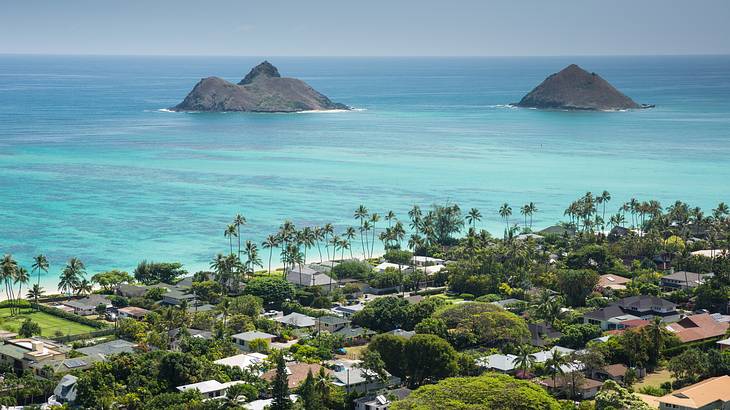 A tropical beach town with turquoise ocean and grey mountains behind it