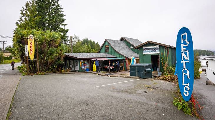 A driveway next to a small building with surfboard signs saying "surf" and "rentals"