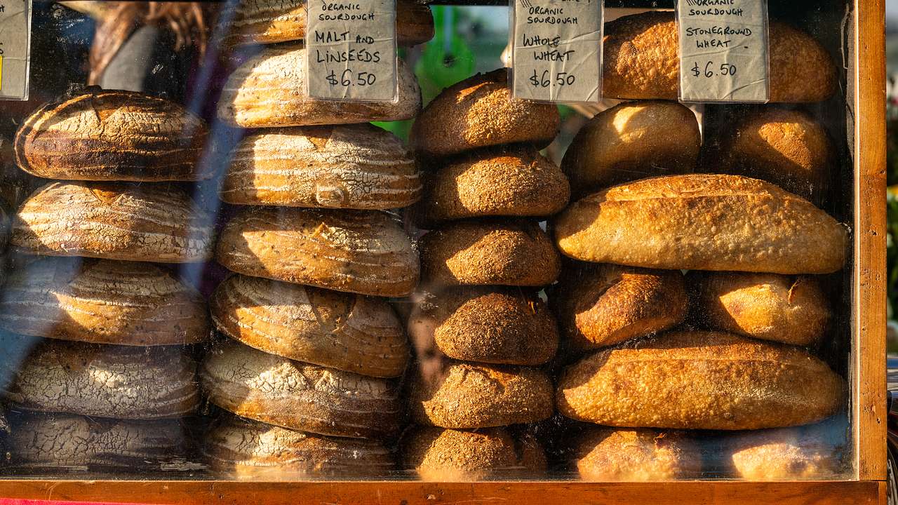 Stacks of bread in a window display, with price tags at the top, at a market