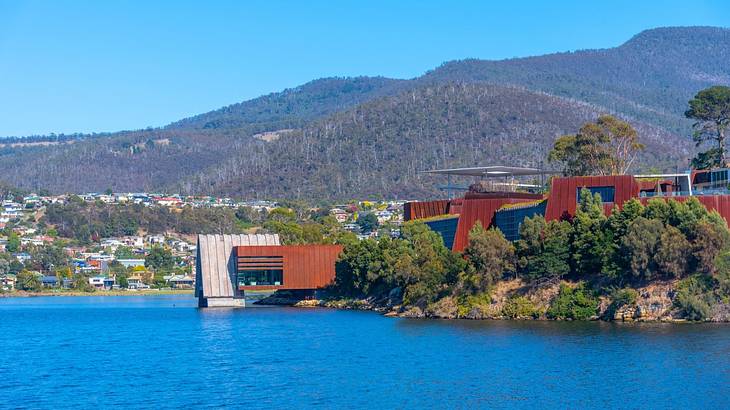 A body of water next to greenery and a building with wood paneling