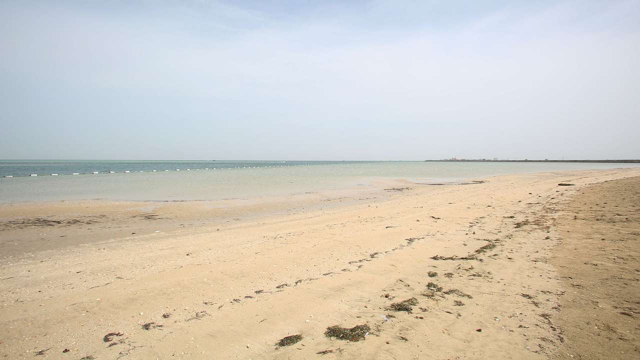 A sandy coast next to the sea under a hazy blue sky