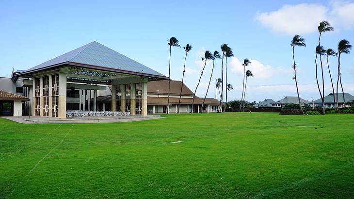 A building with an open front next to green grass and palm trees