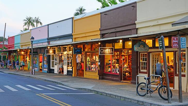 A street with colorful shops next to a road under an overcast sky