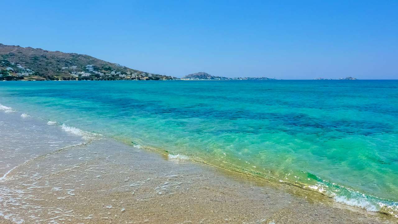 A beach with clear waters near a mountain