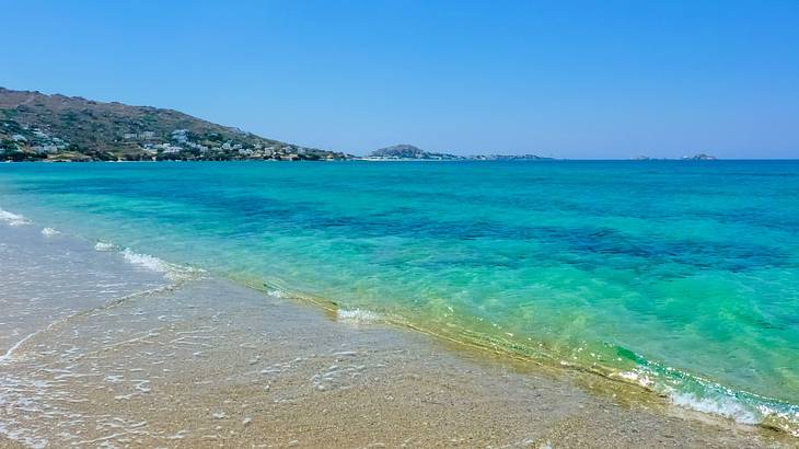 A beach with clear waters near a mountain