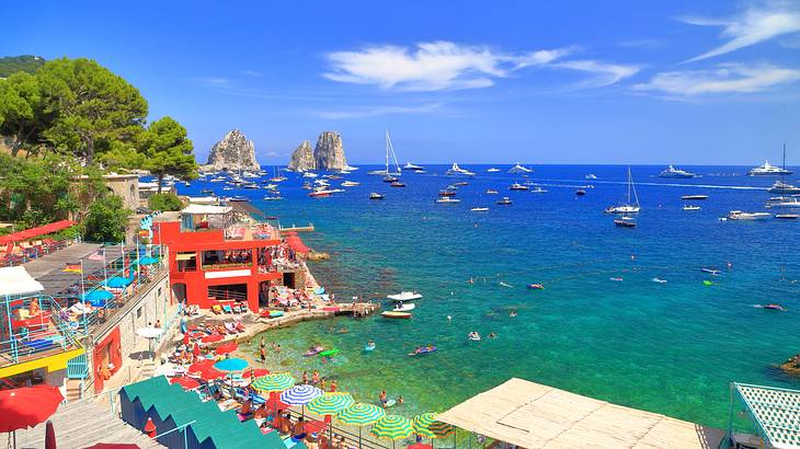 A beach with people lounging and swimming next to colorful buildings