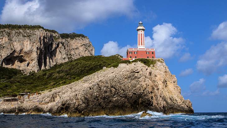 A white and red lighthouse atop a rocky headland