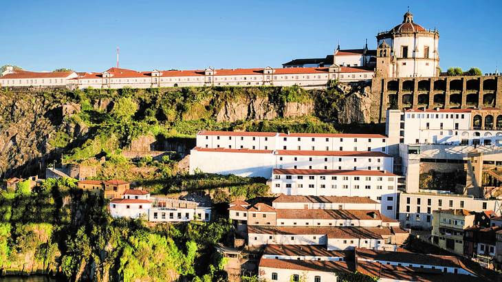 White houses with red roofs situated on steep terrain near a body of water