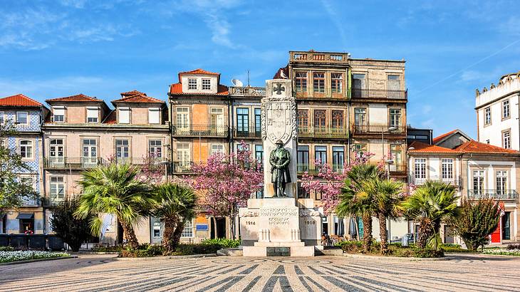 A statue on a pedestal with adjacent houses in the background