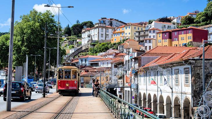 People looking at traditional buildings on a sloping terrain near trams and vehicles