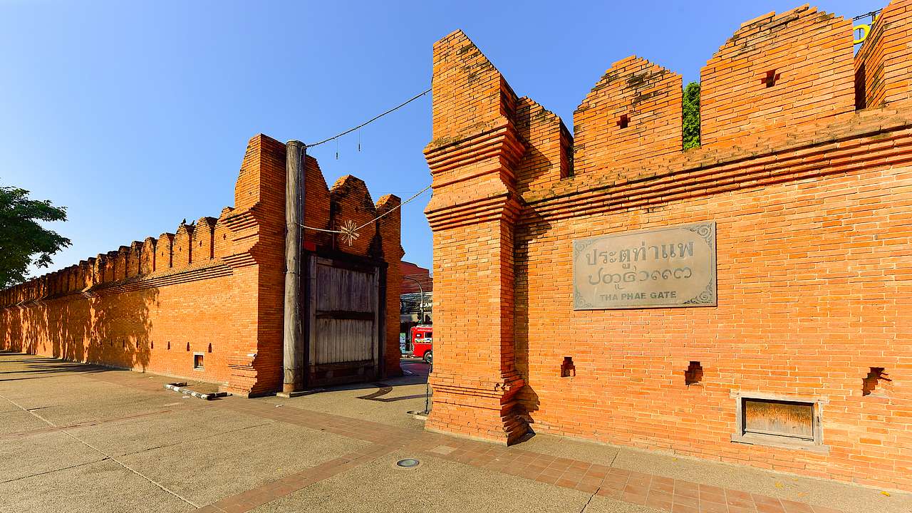 An old gate and wall made of bricks as seen from the street on a sunny day