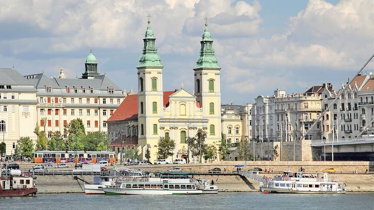 A church with two spires near buildings and a harbor with ships