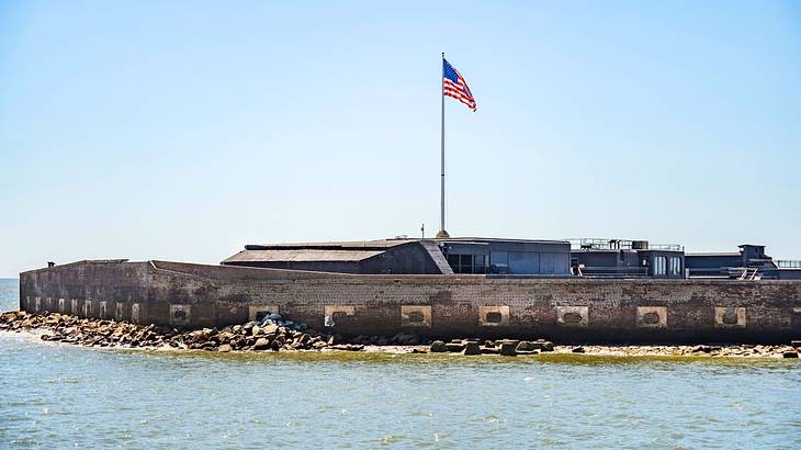 A fort harbor with an American flag on a pole near a body of water