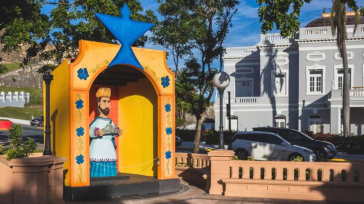 A colorful statue of a king carrying an offering in the corner of a square