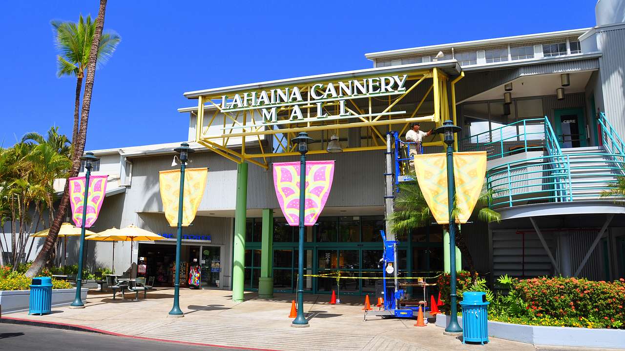 The entrance to a mall with a sign and several banners on lampposts