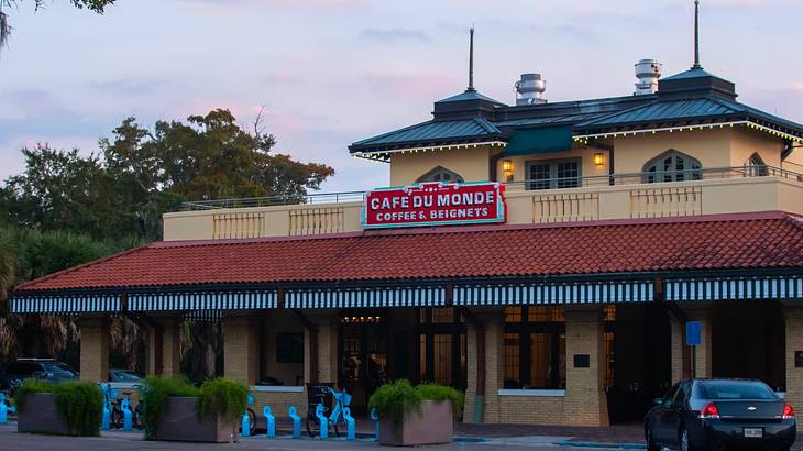 A building with a sign that says "Cafe du Monde" under a sunset sky