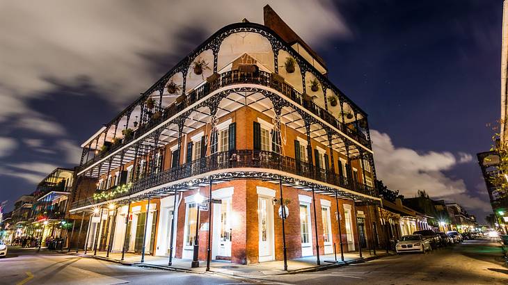 A red brick building with an iron balcony at night